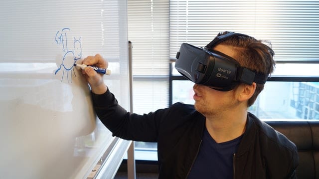 homem com óculos de realidade virtual escrevendo em um quadro branco