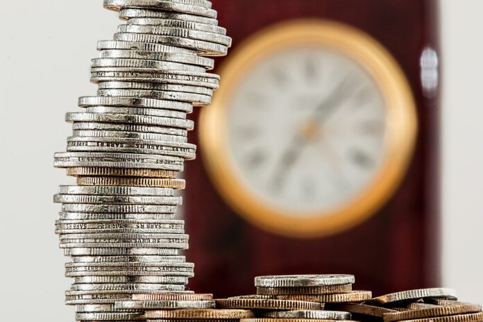 13º salário pilha de moedas com um relógio de parede ao fundo
