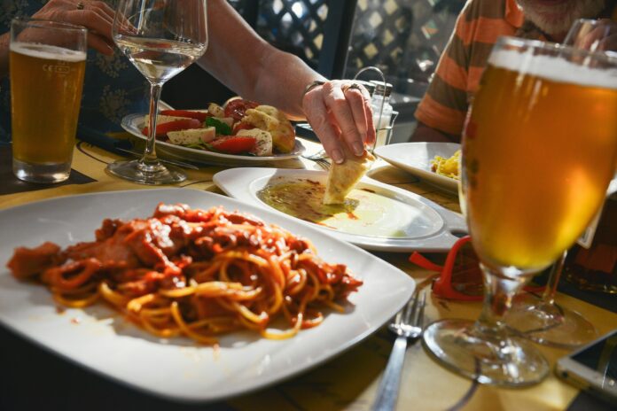 Duas pessoas comendo massas com cerveja