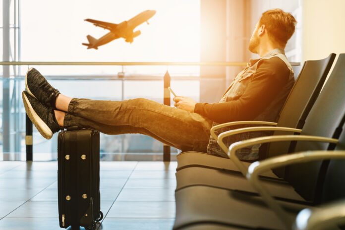 Homem sentado com sua mala, olhando para avião em aeroporto