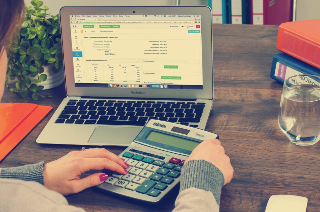 mulher usando calculadora e notebook na mesa de trabalho