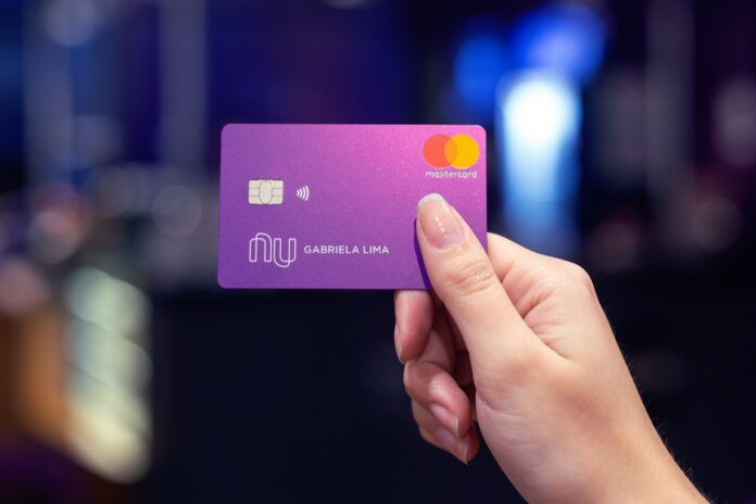 Mulher segurando cartão de crédito do Nubank