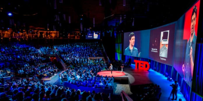 Palco do Ted Talks com palestrante se apresentando e platéia cheia
