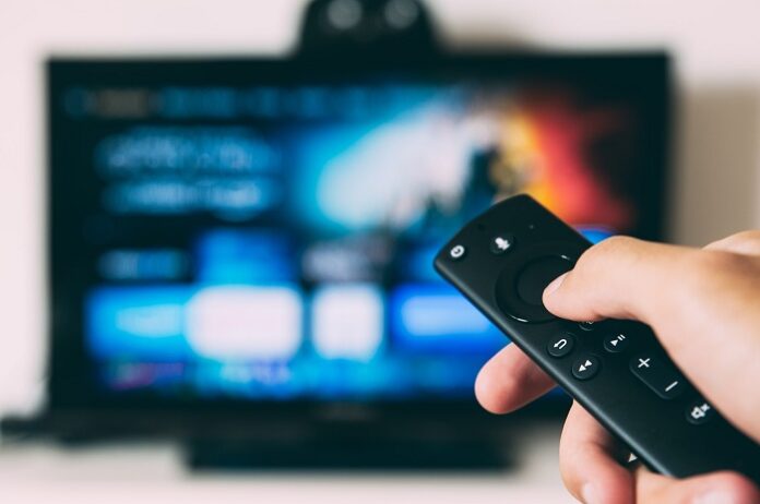 pessoa apontando controle para a tv