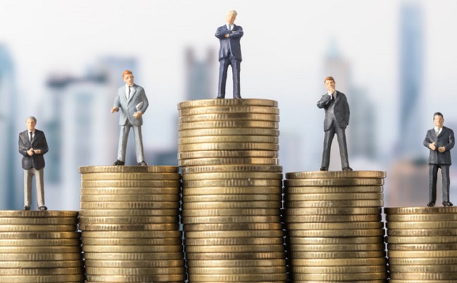 pilha de moedas com bonecos representando pessoas ricas