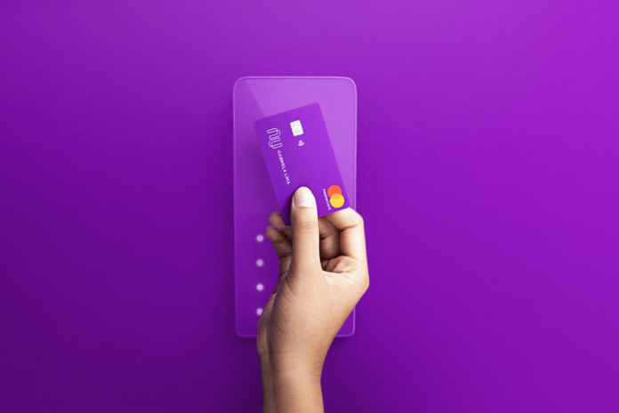 Nubank lança cartão Pessoa segurando cartão do nubank em um fundo roxo