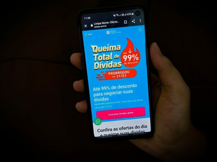 Tela de smartphone acessando a queima total de dívidas do Serasa
