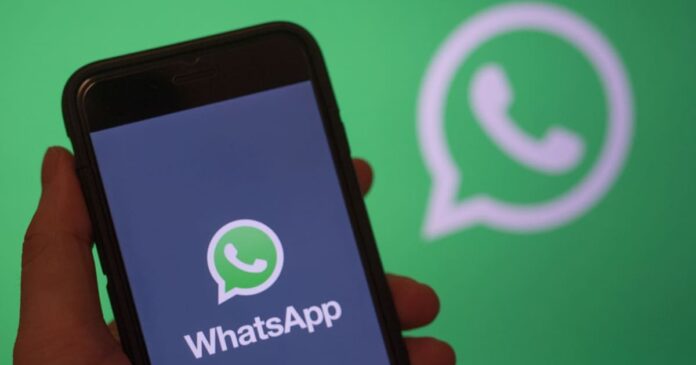 Mão segurando celular com app do WhatsApp