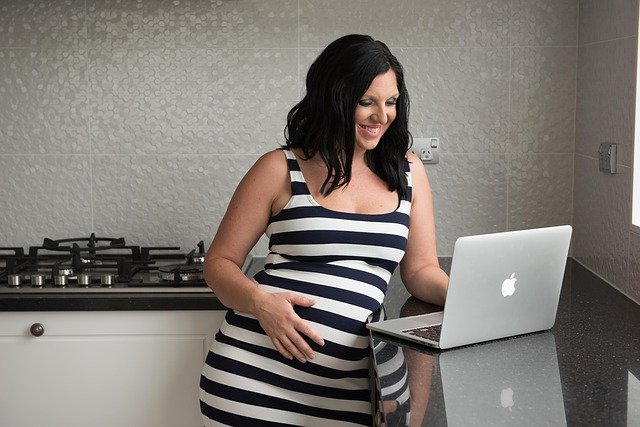 gestante com a mão na barriga e trabalhando