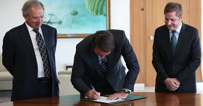 presidente Bolsonaro assinando a medida provisória ao lado de ministros