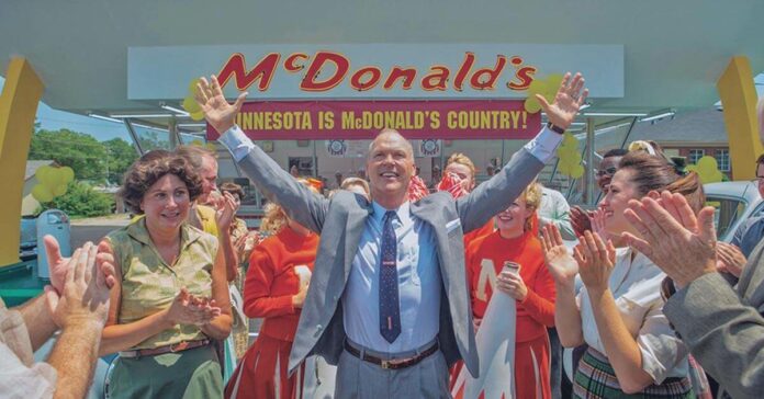 Cena congelada do filme Fome de Poder em que o empresário Ray Kroc estende os braços em frente a uma franquia do McDonald's