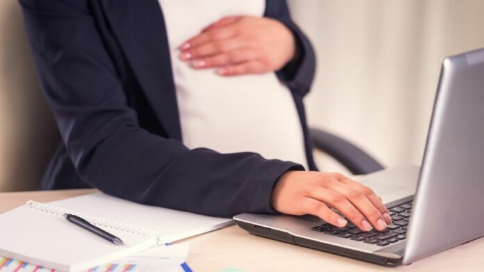 Empreendedora grávida sentada em frente a computador