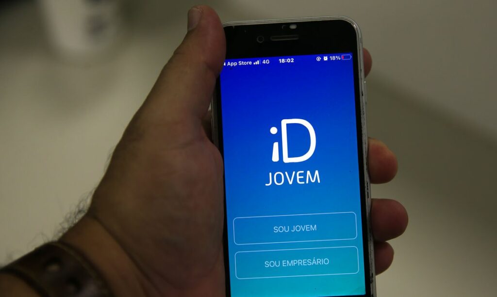 Pessoa segura celular na mão com aplicativo da ID Jovem na tela