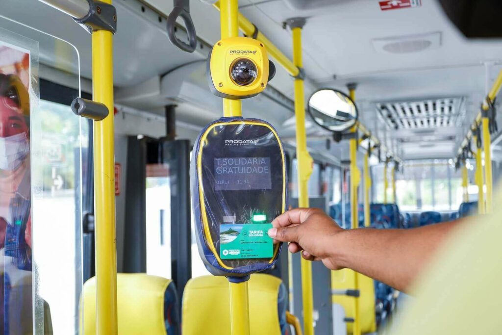 Homem aponta o cartão Tarifa Solidária de Prefeitura de Saquarema para o leitor de cartões do ônibus