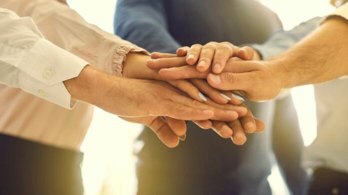 economia solidaria Grupo de pessoas com as mãos umas sobre as outras