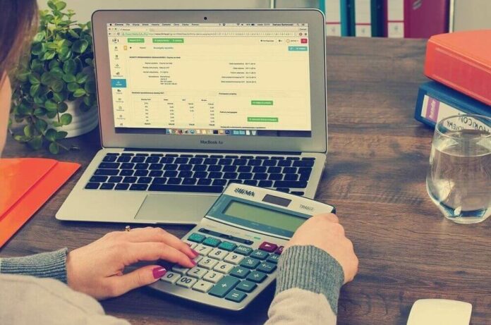 dctf Mulher emite DCTF em um computador com uma calculadora ao lado