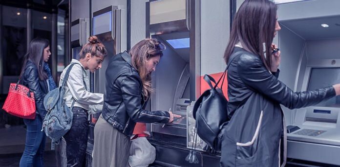 quatro mulheres enfileiradas usando o caixa eletrônico