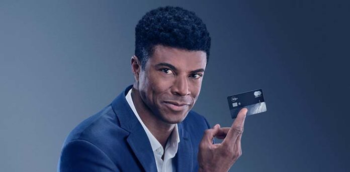 Homem segurando cartão do banco BTG