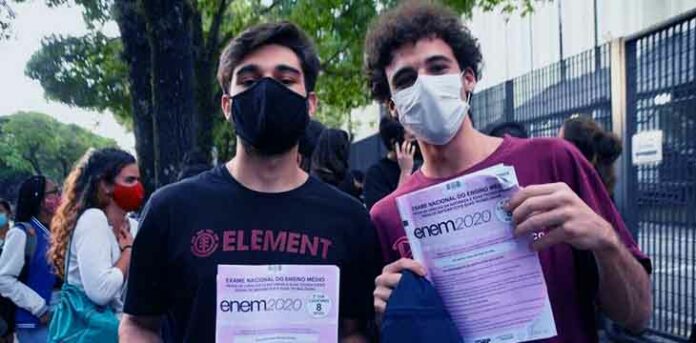 Dois meninos segurando o caderno de questões do Enem