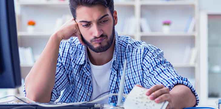 Homem lê uma reclamação trabalhista com expressão de dúvida