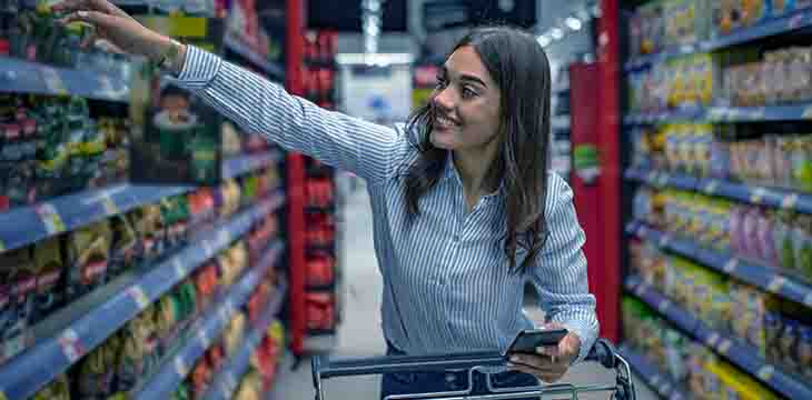 Garota pegando produtos na prateleira do supermercado