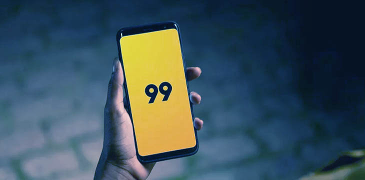Pessoa segurando celular com logo da 99 na tela