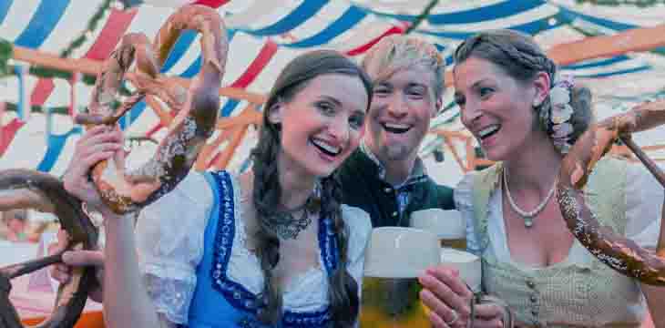 Duas mulheres e um homem com trajes típicos alemãs na Oktoberfest